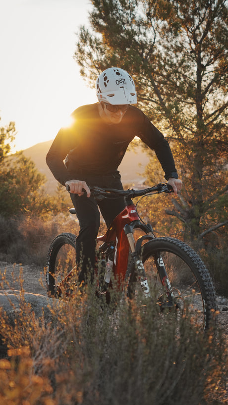 Mountainbiker in schwarzen Klamotten auf rotem Fahrrad