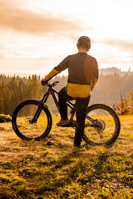 Mountainbiker steht mit dem Rücken und guckt in die Berge