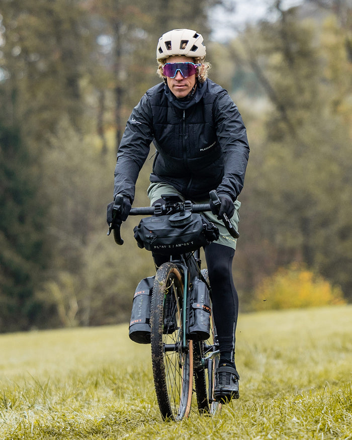 Gravelbiker trägt schwarze Weste und grüne Shorts