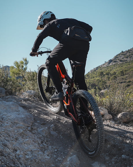 Mountainbiker auf rotem Mountainbiker fährt Berg hoch